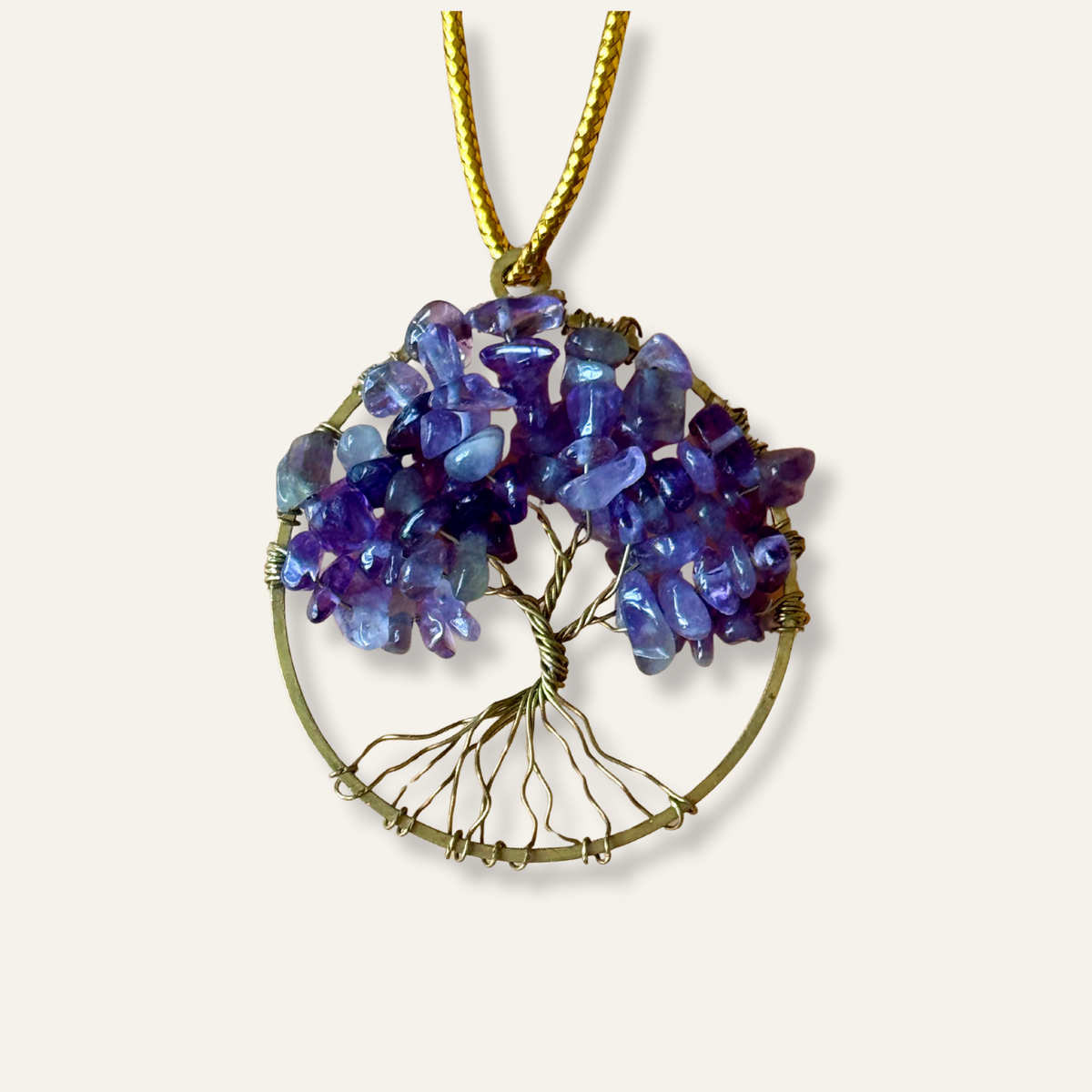 Tree of Life pendant with purple gemstones amethyst and brass wirework on a white background