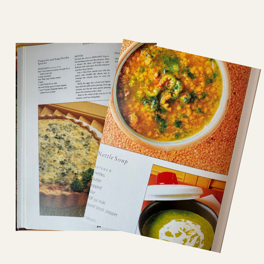Open vegetarian cookbook showing recipe text and photographs of soups and a quiche.