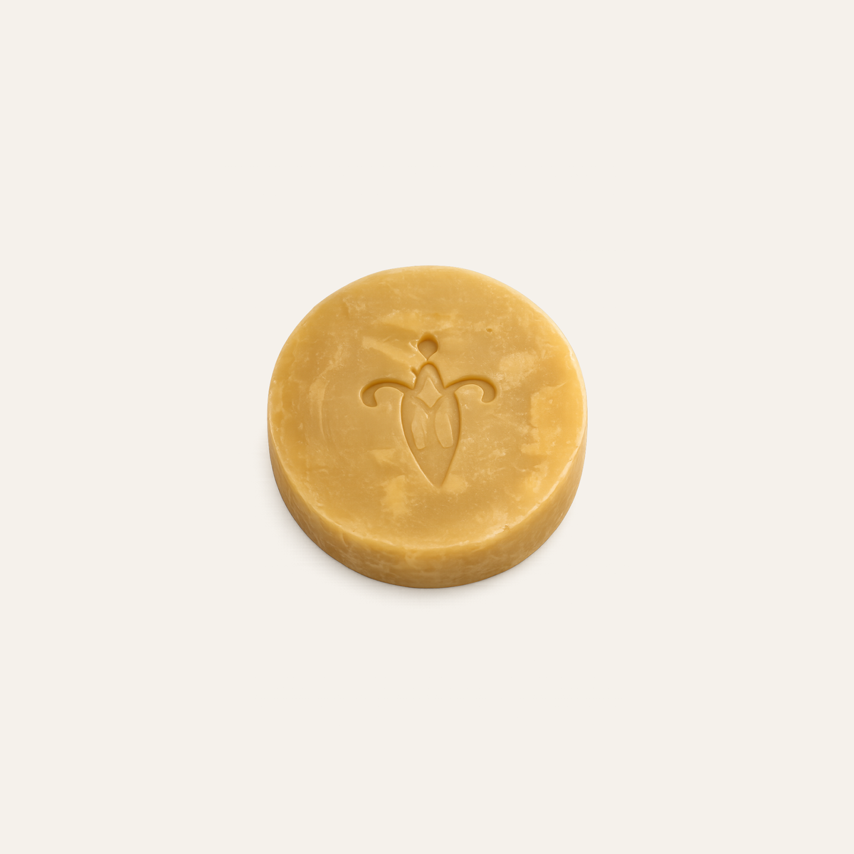 Round yellow bar of soap with a logo on a light beige background