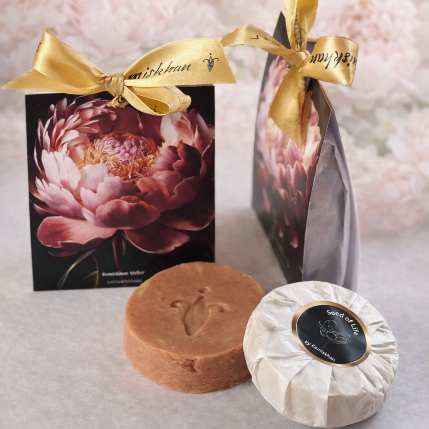 Two soaps, one pink and one in white wrap, with premium decorative boxes featuring floral designs on a light background.