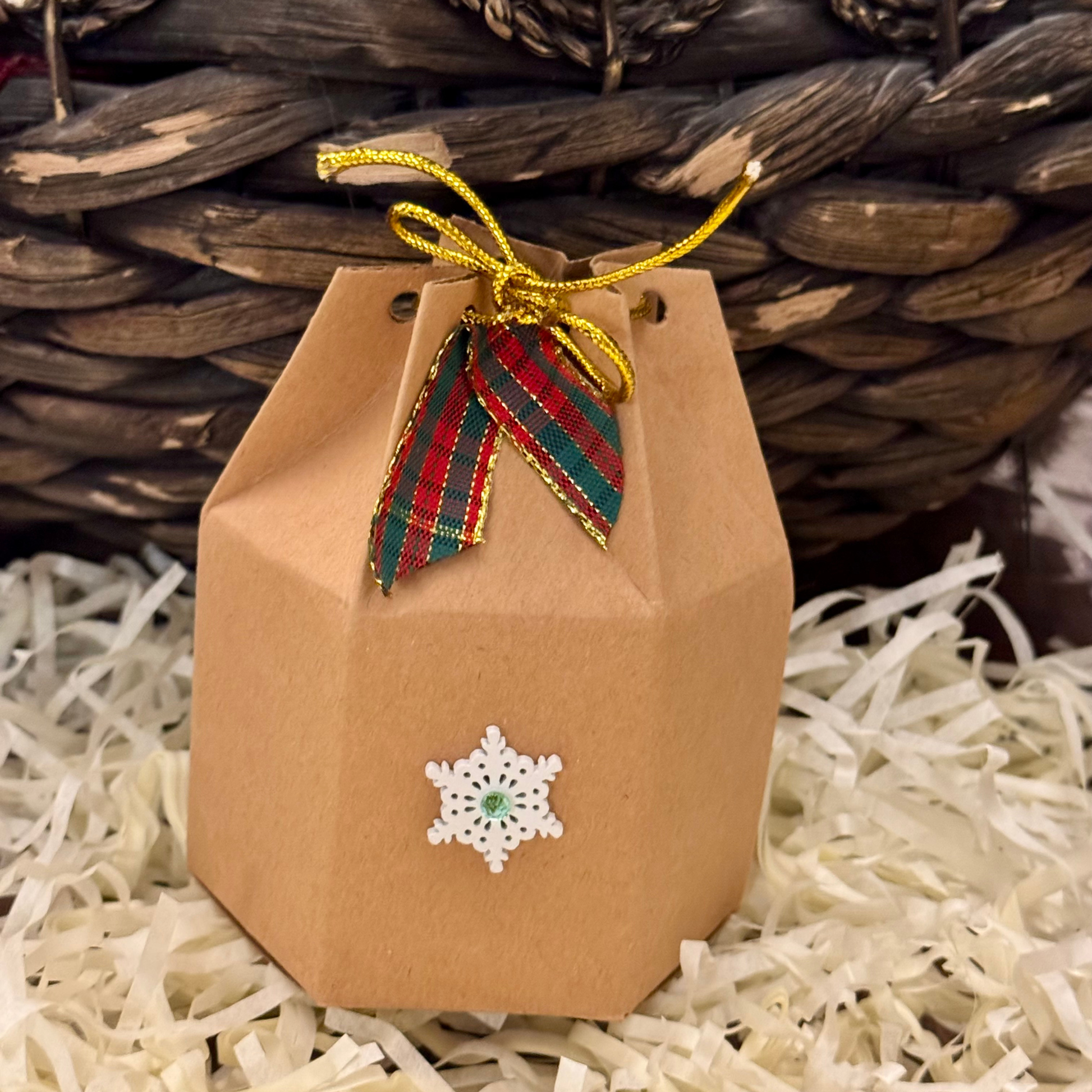 Brown paper bag with a snowflake design and colorful ribbon against a woven basket background.pack for candle