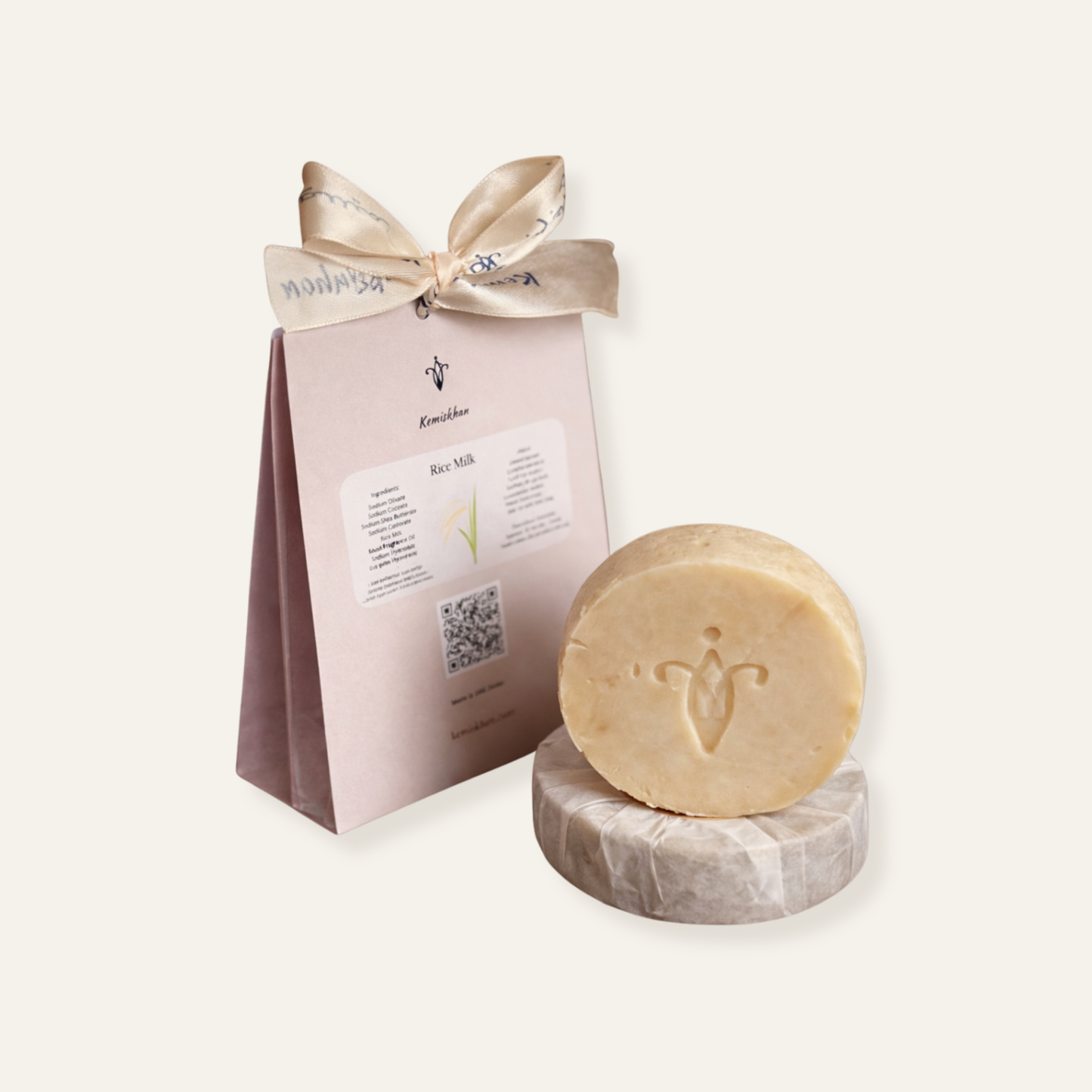 Bar of rice milk soap on a marble stand with a branded pink packaging sleeve on a white background
