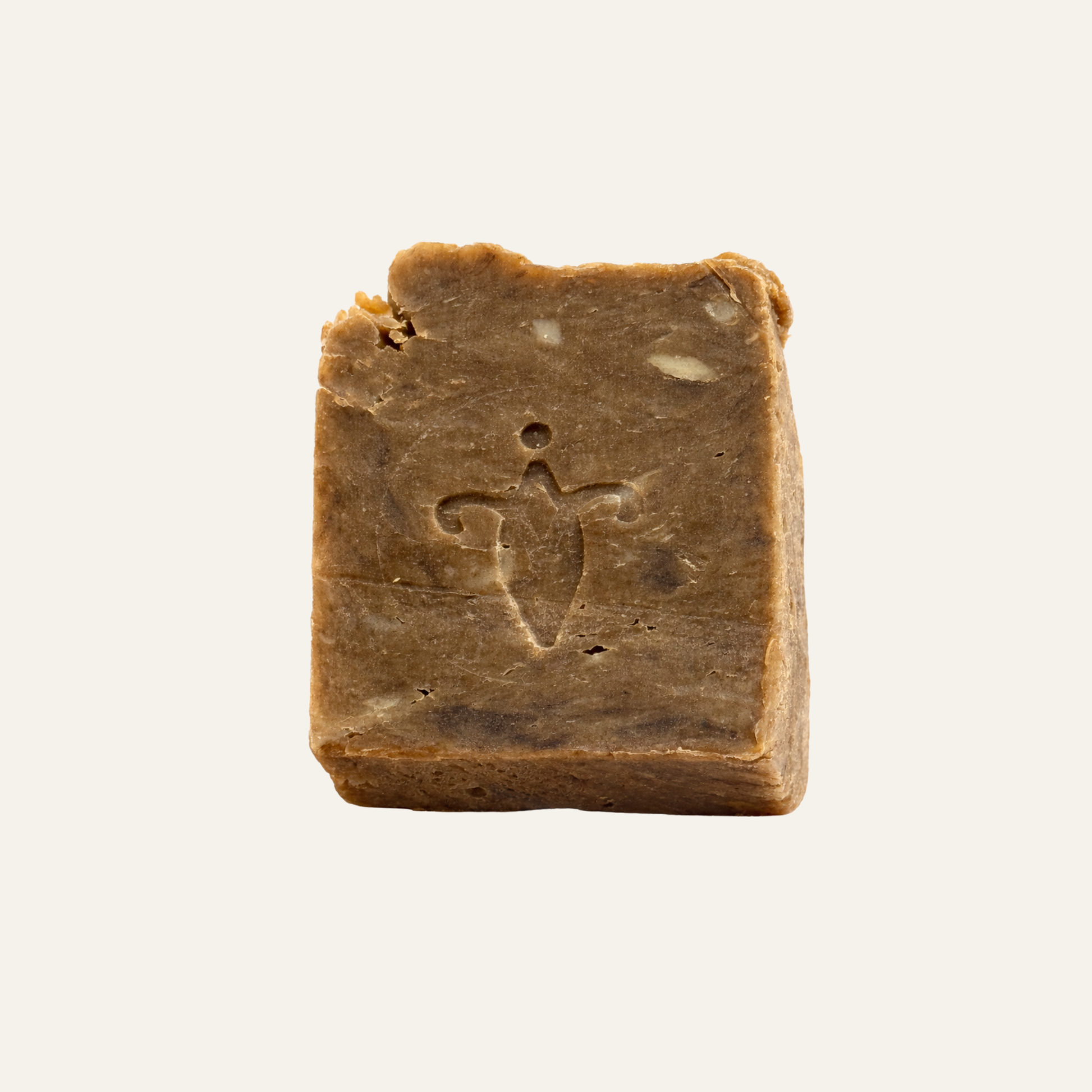 Square piece of brown soap  of birch tar, with a logo on a light beige background