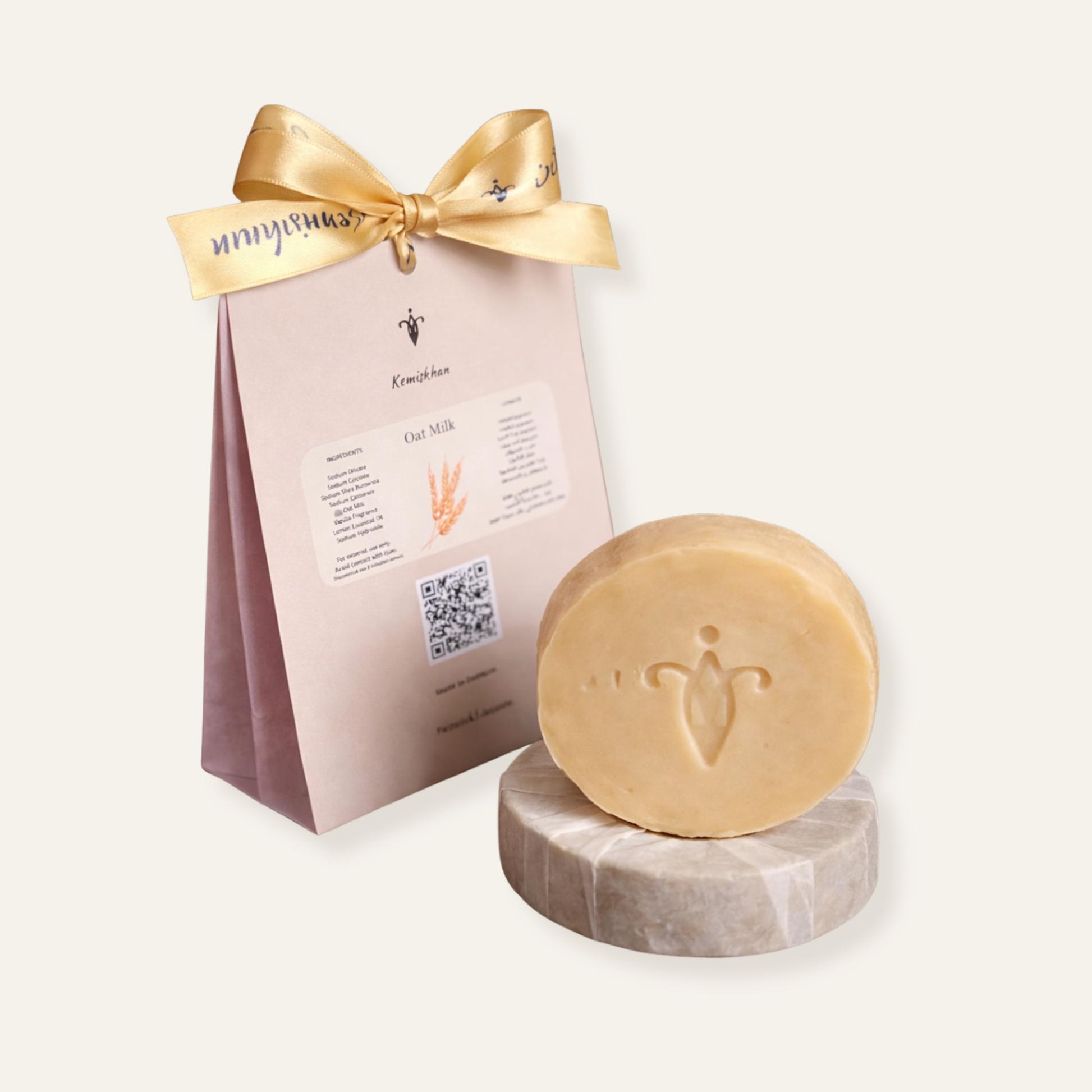 Bar of soap on a wrapped sopa with a branded pink packaging sleeve featuring a gold bow.